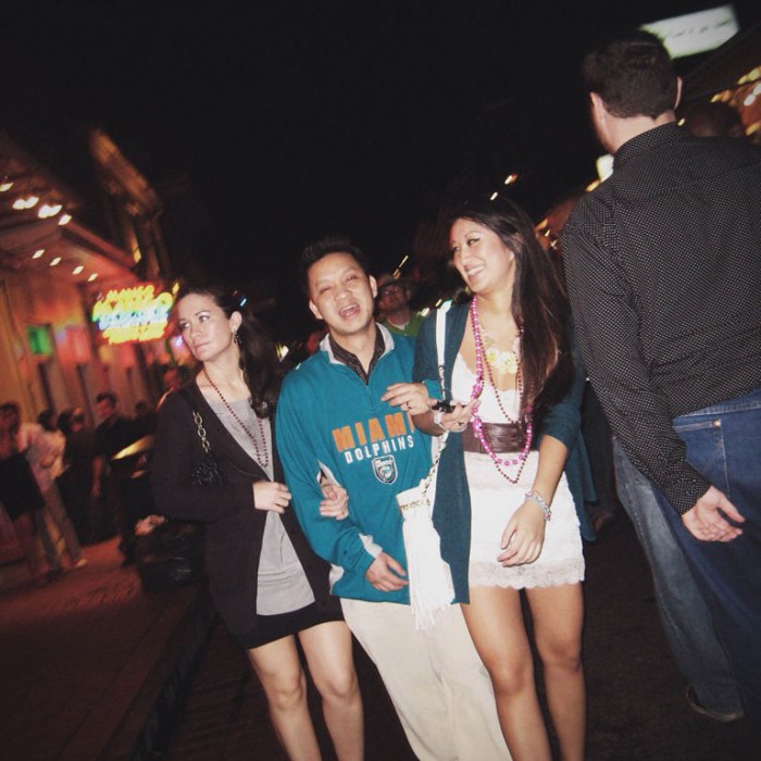 dolphins fan with two young ladies in short dresses on each arm on bourbon street